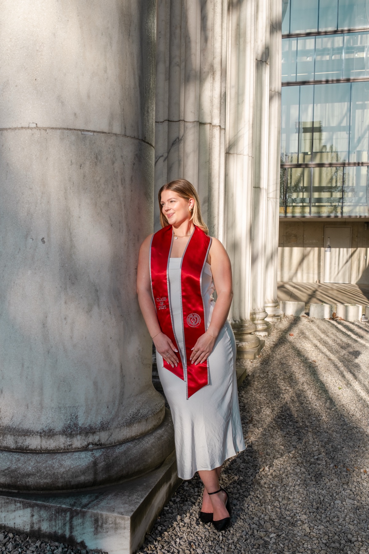 Graduate in a red stole leaning against a pillar