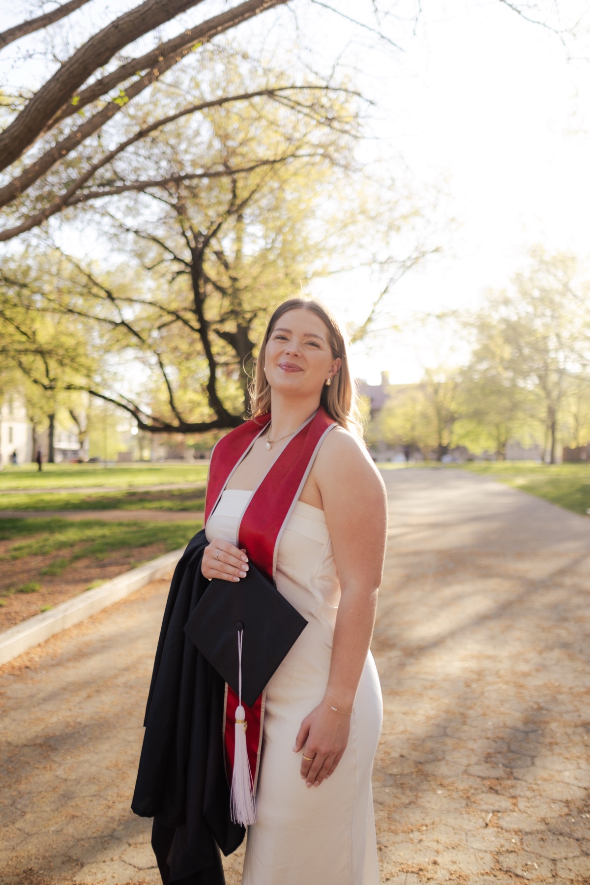 Graduate in a red stole walking a path
