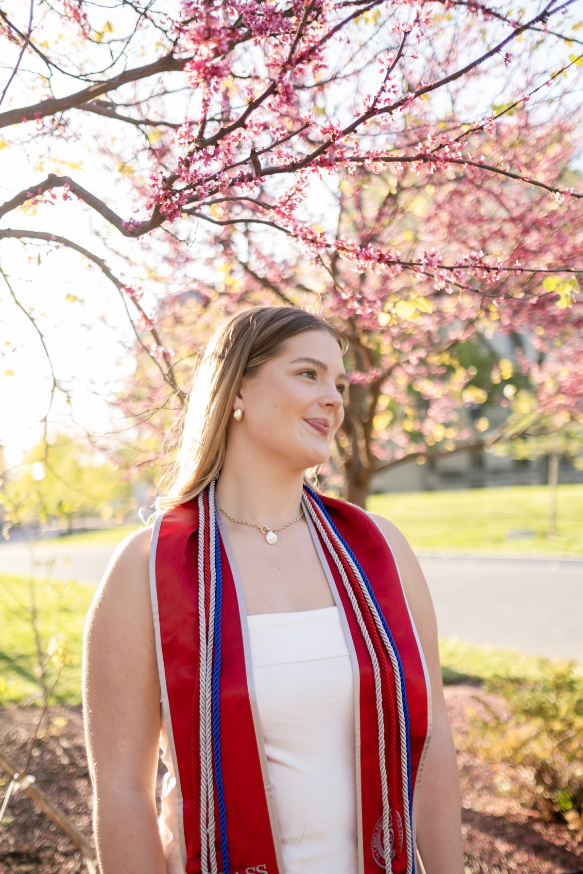 Graduate in a red stole among cherry blossoms