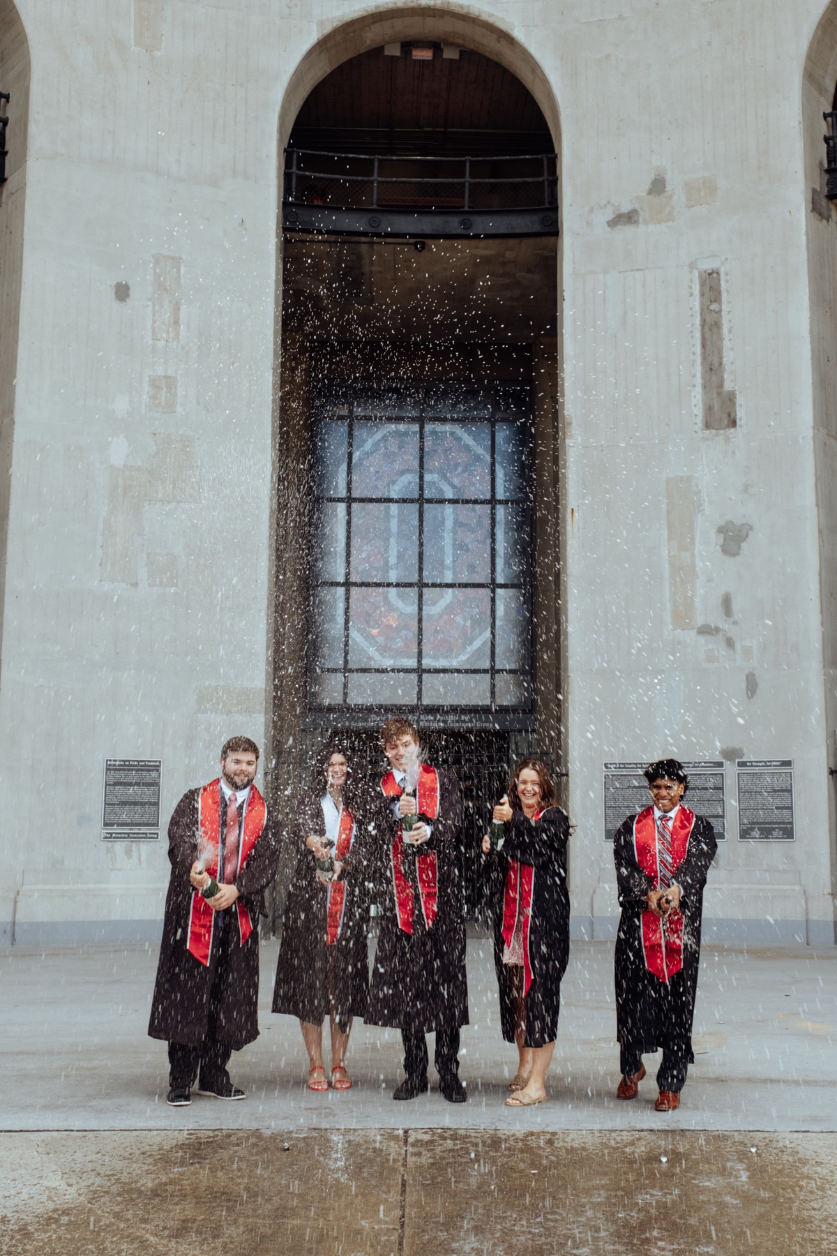 Group of graduates celebrating at a campus archway