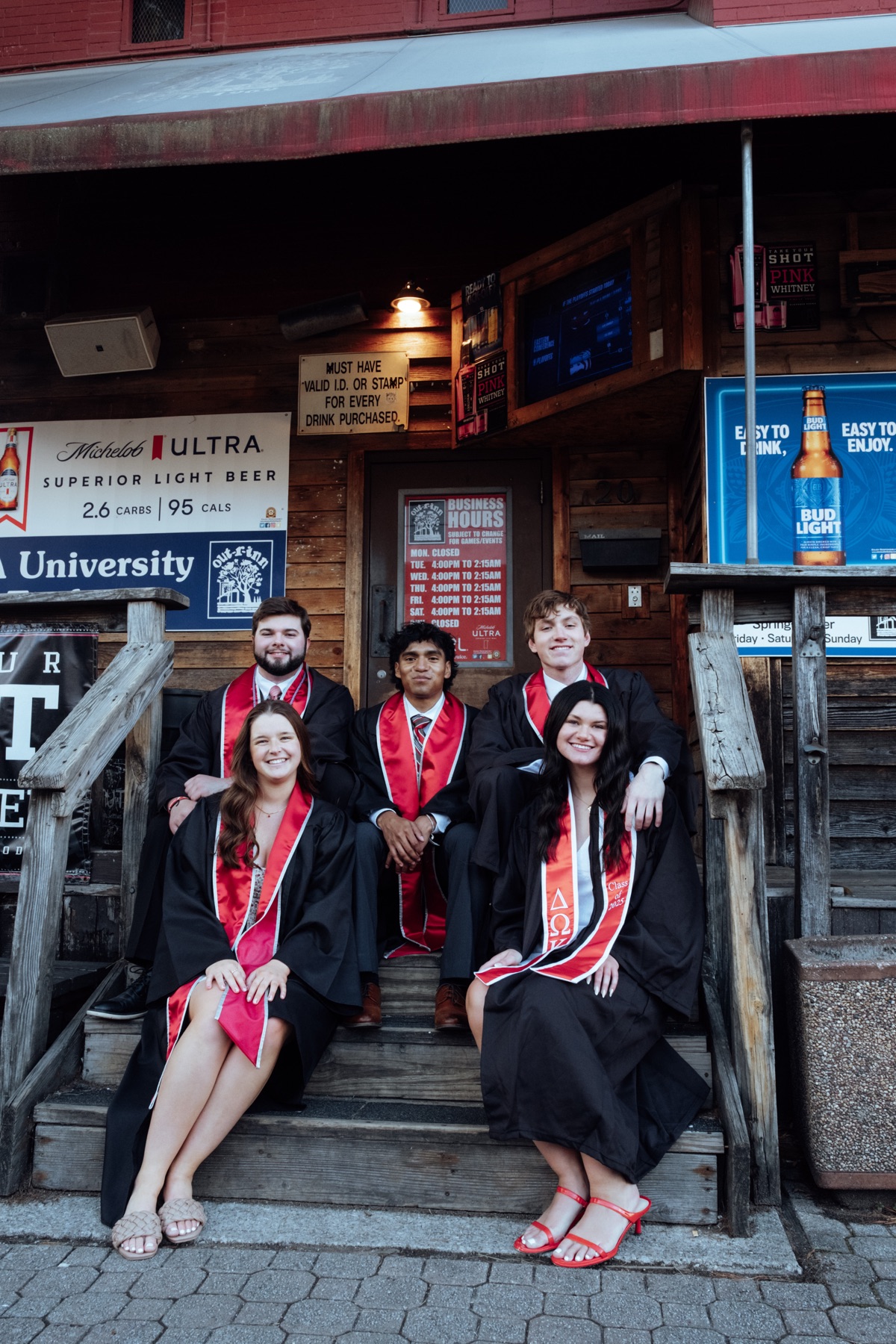 Graduates sitting together on wooden steps