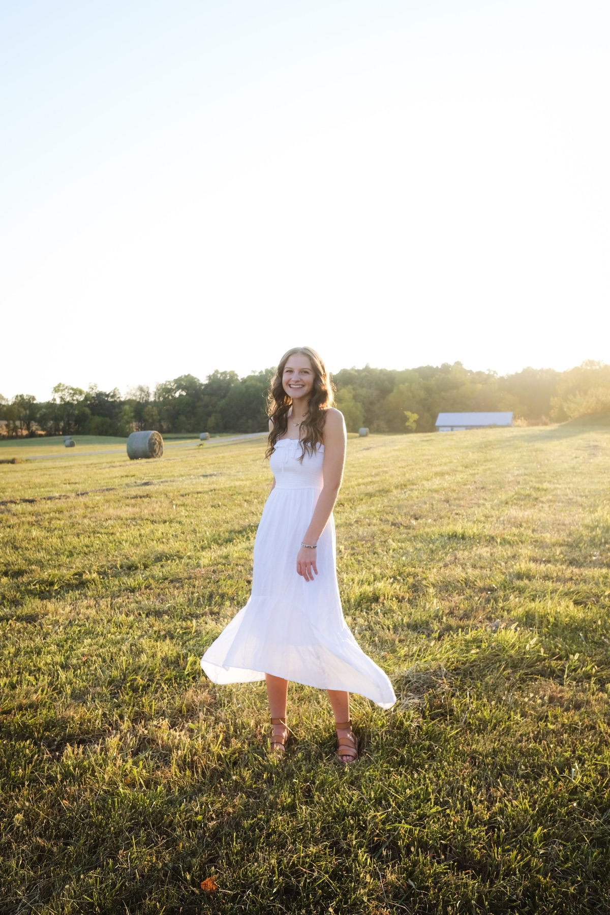Senior portrait in a white dress in an open field