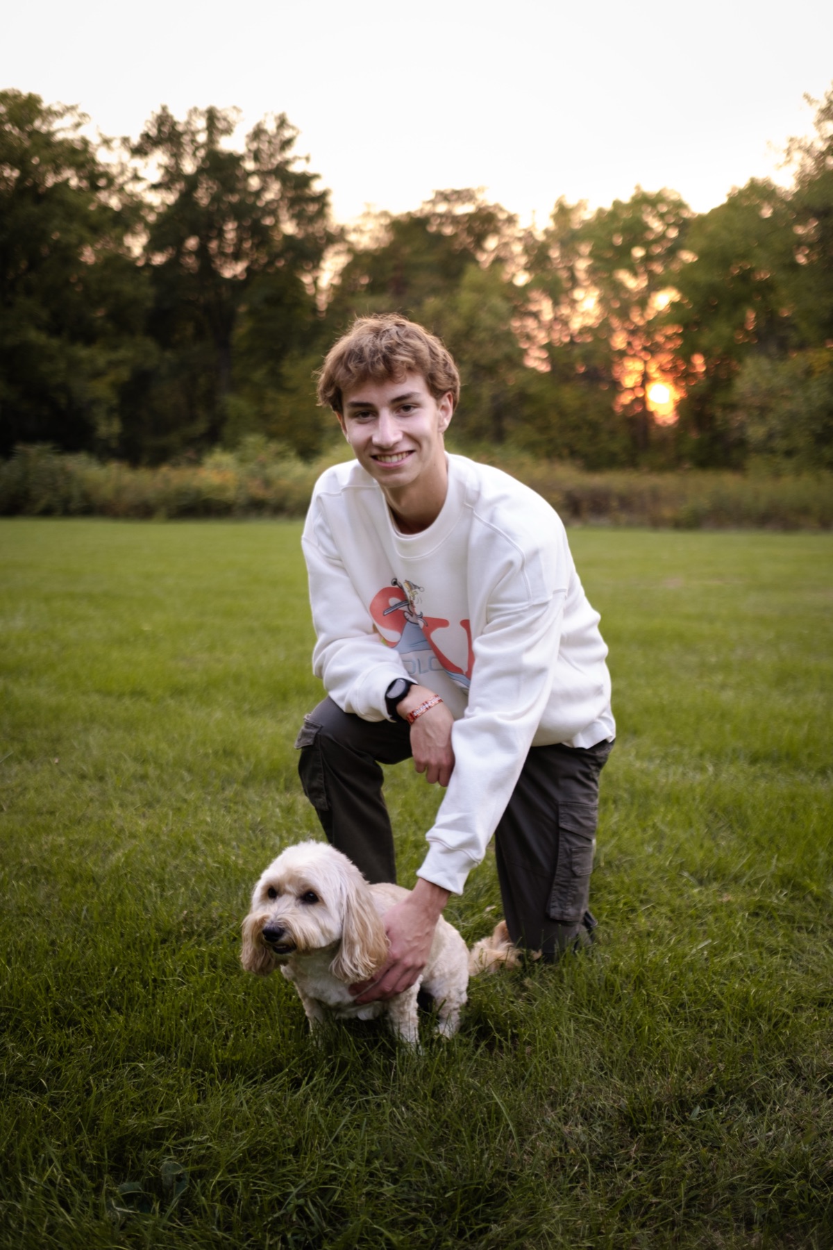Senior portrait kneeling with a dog in a field