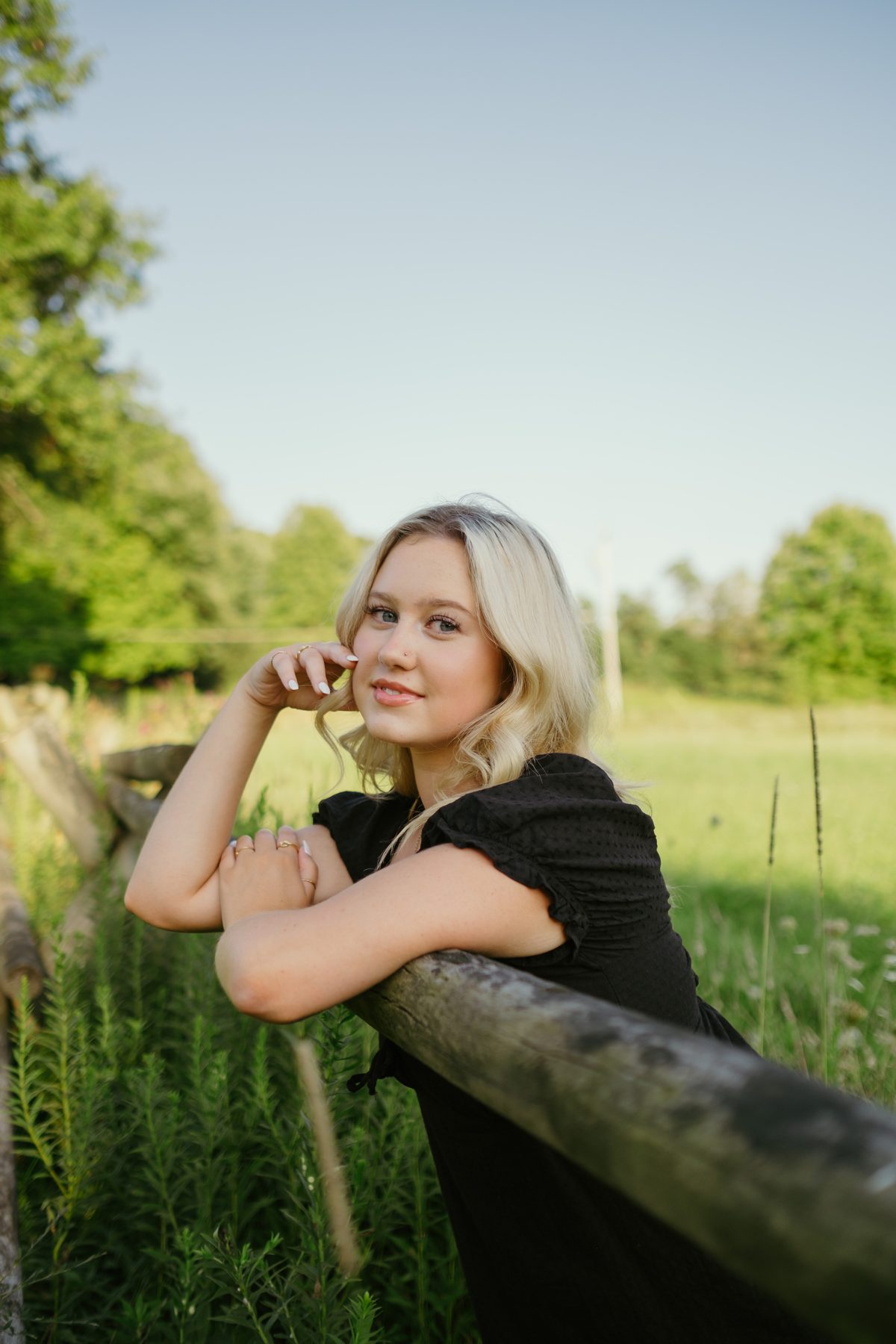 Senior portrait resting on a fence rail at golden hour