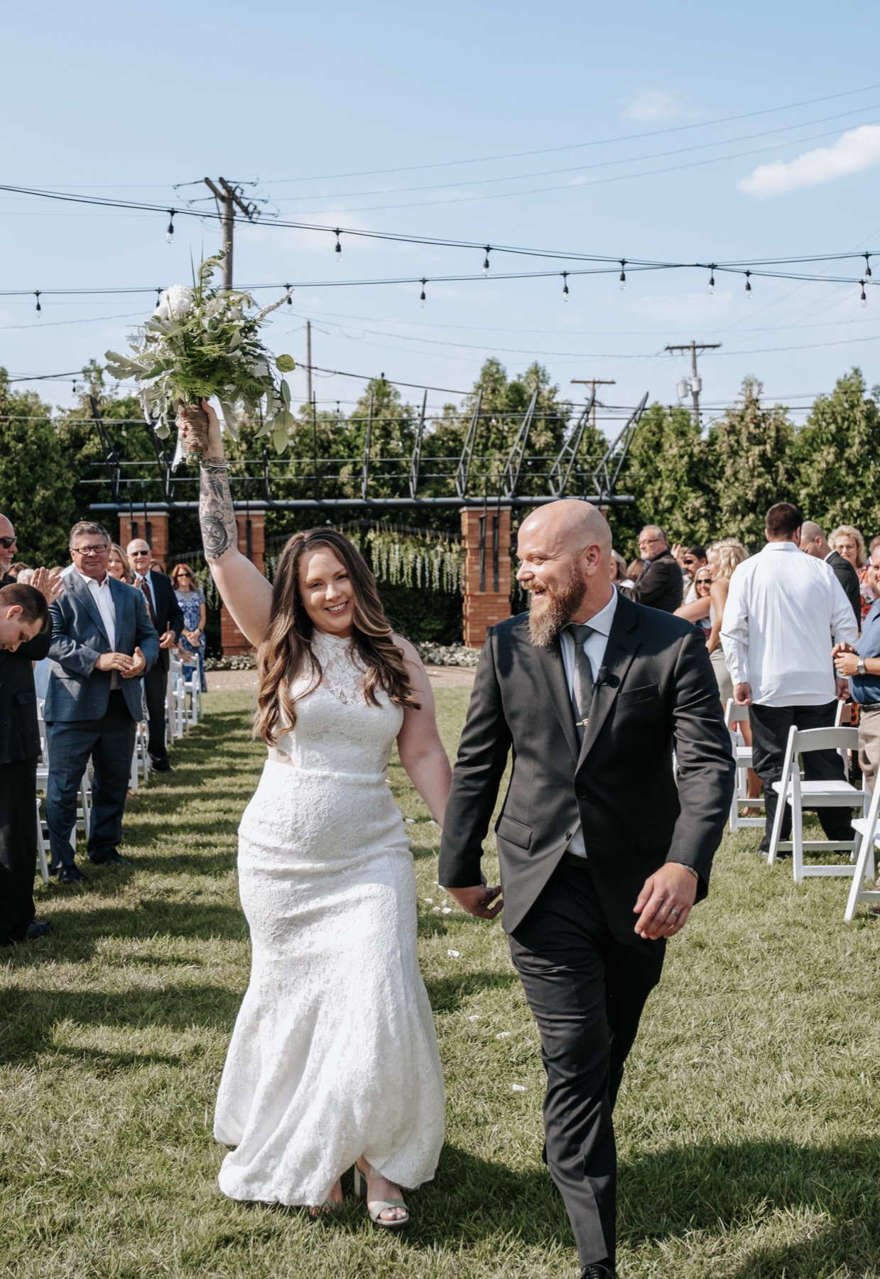 Bride and groom walking under string lights at their ceremony